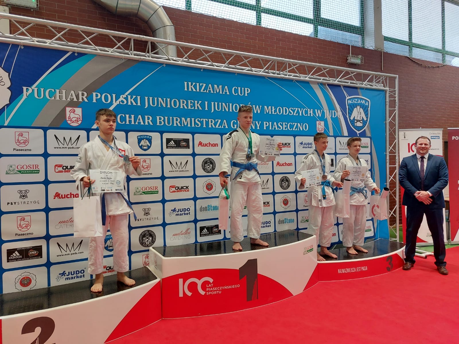 Podium na którym stoi czterech medalistów. Na miejscu nr 1 (drugi z lewej) - Jakub Kurowski.