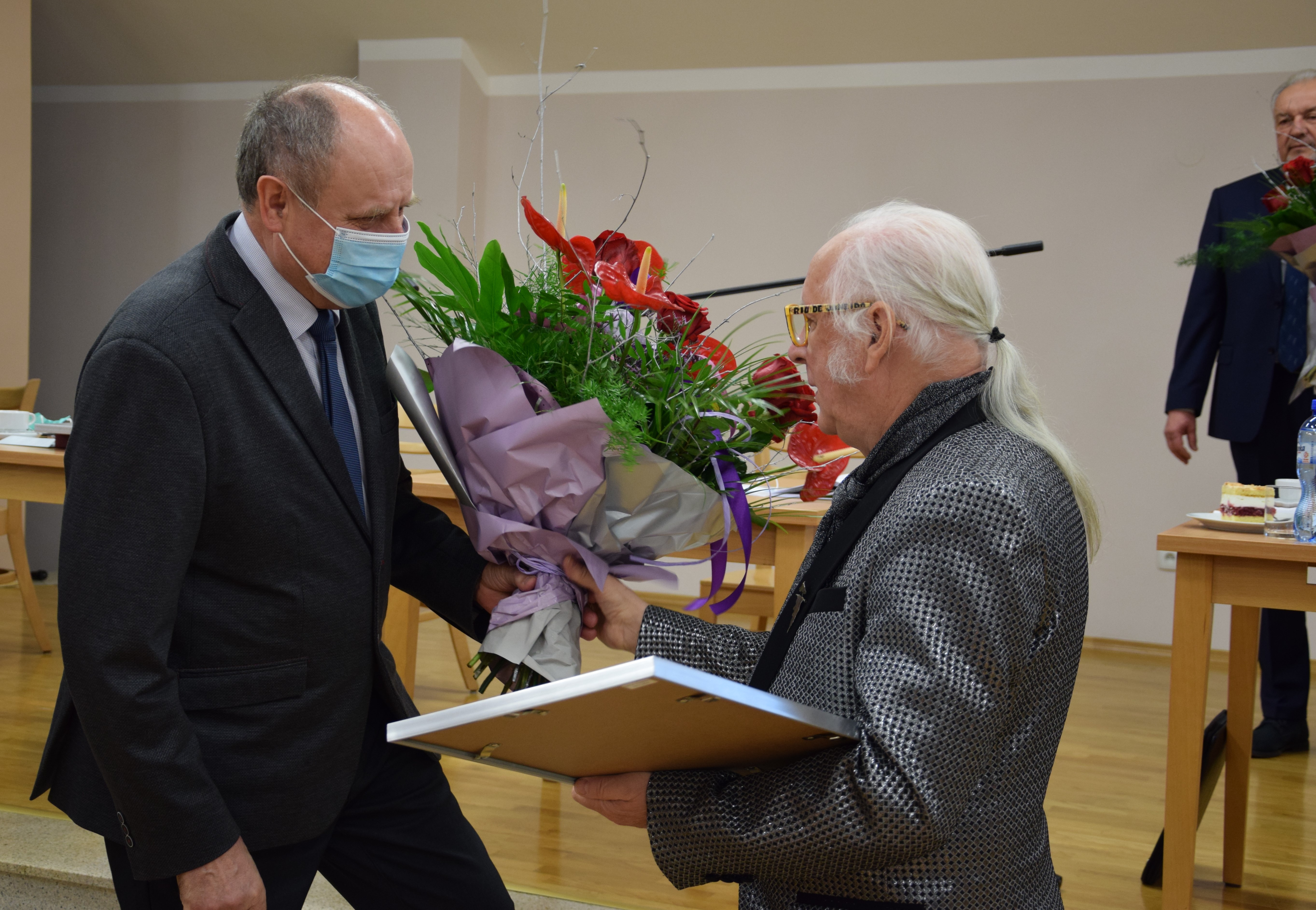 Na scenie widowiskowej GOKu, przewodniczący rady gminy wręcza Florianowi Kohutowi kwiaty.
