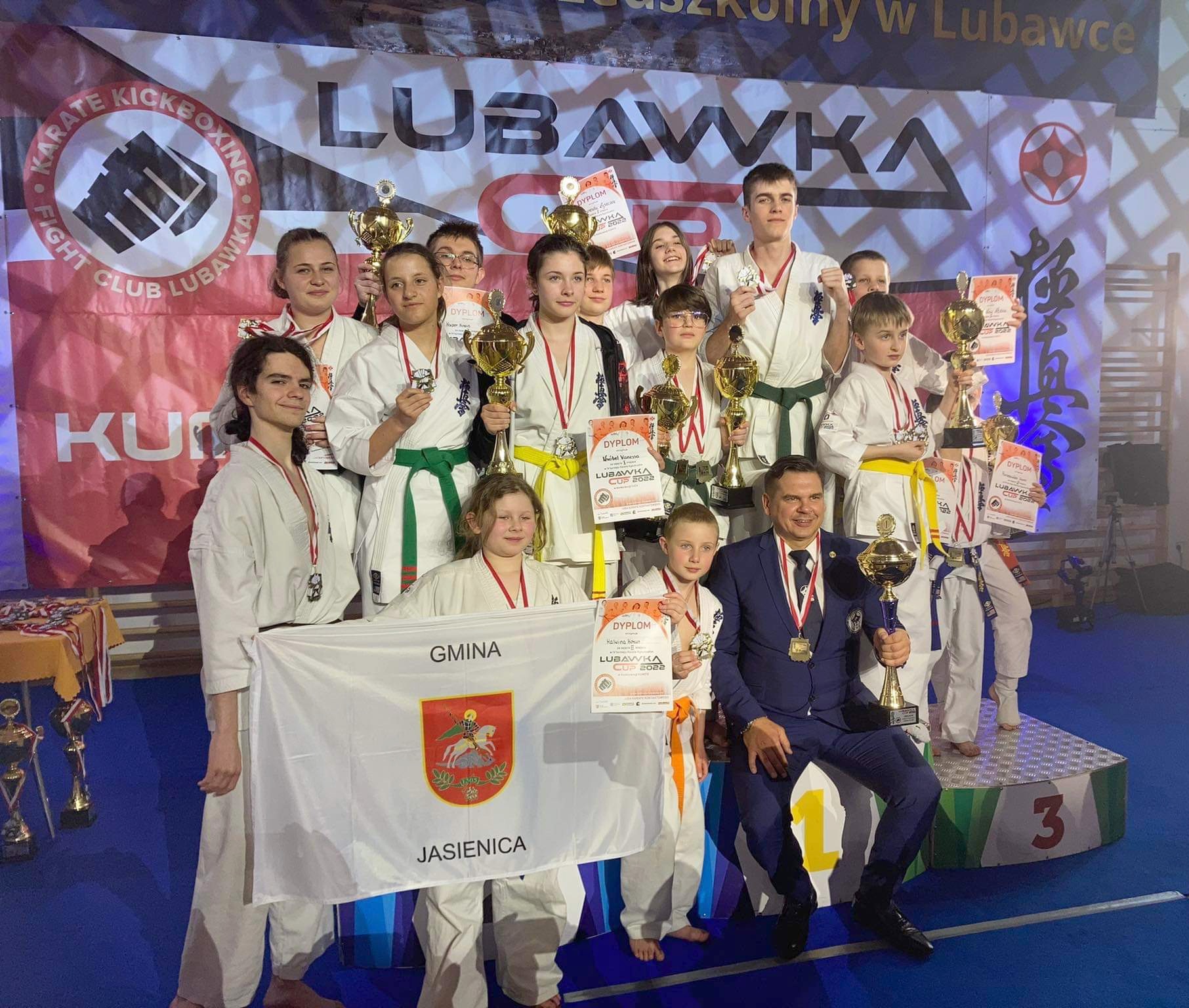 Drużyna bielskiego klubu karate. Malwina w rękach trzyma flagę herbu gminy Jasienica.