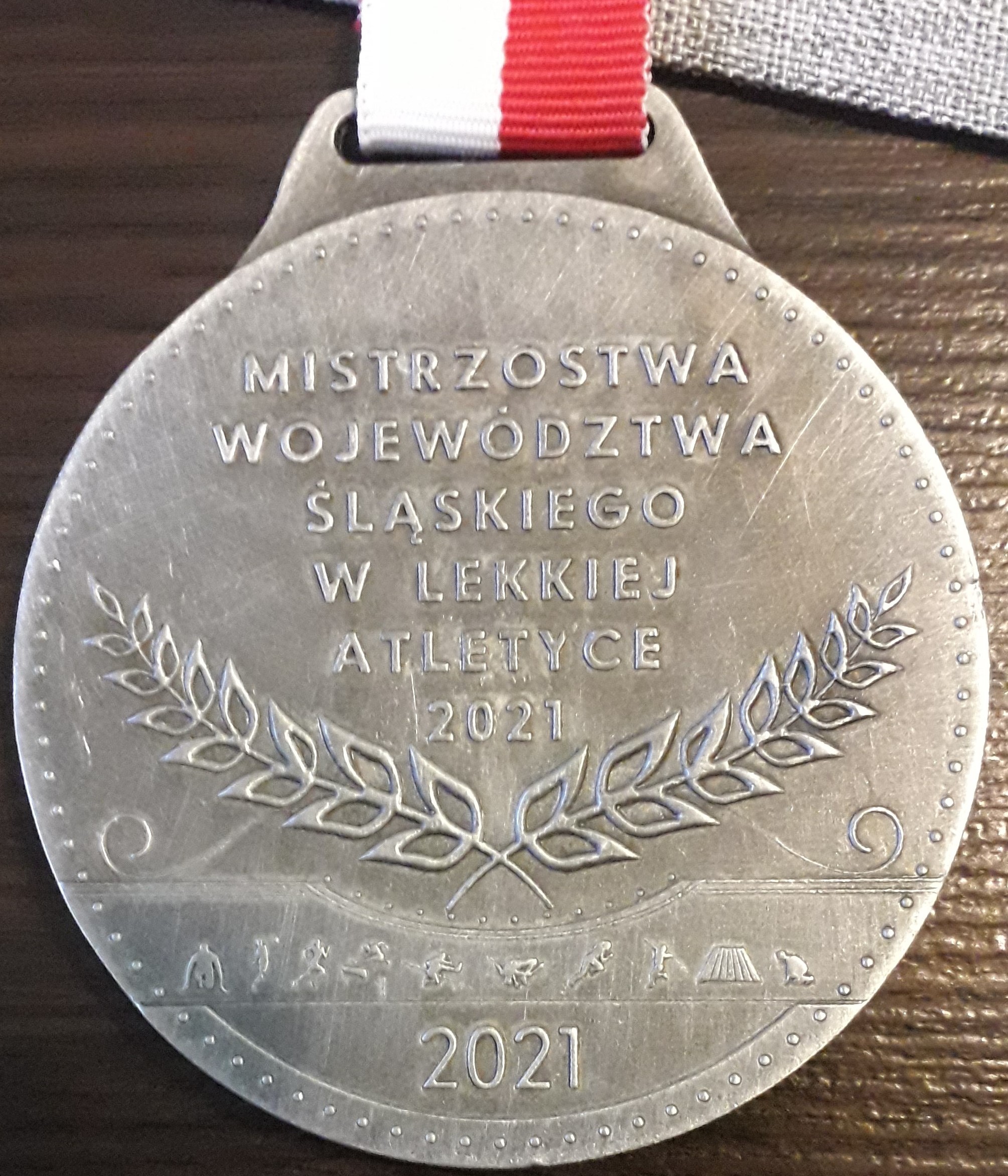 Srebrny medal z wygrawerowaną nazwą zawodów Mistrzostw Województwa Śląskiego w Lekkiej Atletyce.