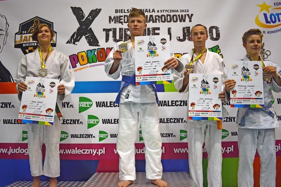 Zdjęcie przedstawia zawodników na podium. Na pierwszym miejscu drugi z lewej Kuba Kurowski wraz z medalem i dyplomem.